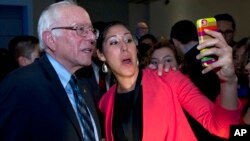 Una mujer hispana se toma un selfie con Bernie Sanders durante un evento del Caucus Hispano.