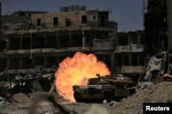 FILE - A tank of the Emergency Response Division fires at Islamic State militants in the old city of Mosul, Iraq, July 5, 2017.
