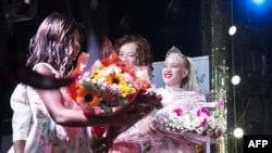 Sithembiso Mutukura, à droite, couronnée Miss albinos-Zimbabwe, reçoit un bouquet de fleurs lors du concours inaugural de beauté de ce genre, à Harare, le 17 mars 2018.