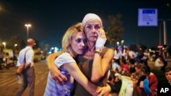 Passengers embrace each other early in the morning as they wait outside Istanbul's Ataturk airport following their evacuation in the wake of a number of explosions, June 29, 2016.