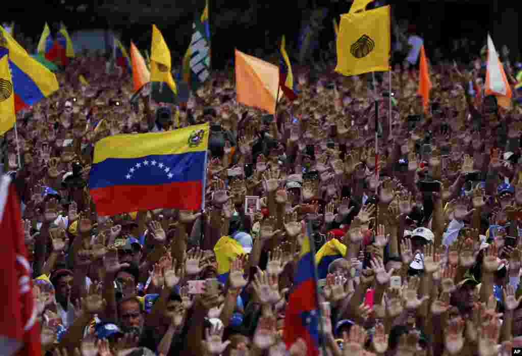 تظاهرات کنندگان ضد دولتی در کاراکاس ونزوئلا دستهای خود را در زمان ادای سوگند نمادین خوان گوایدو به عنوان رئیس جمهوری موقت بالا نگاه داشته&zwnj;اند.