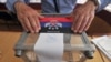 Member of the regional election commission glues sticker depicting flag of the self-proclaimed "Donetsk People's Republic" atop Ukraine's state emblem as he prepares ballot boxes, Donetsk, eastern Ukraine, May 10, 2014.