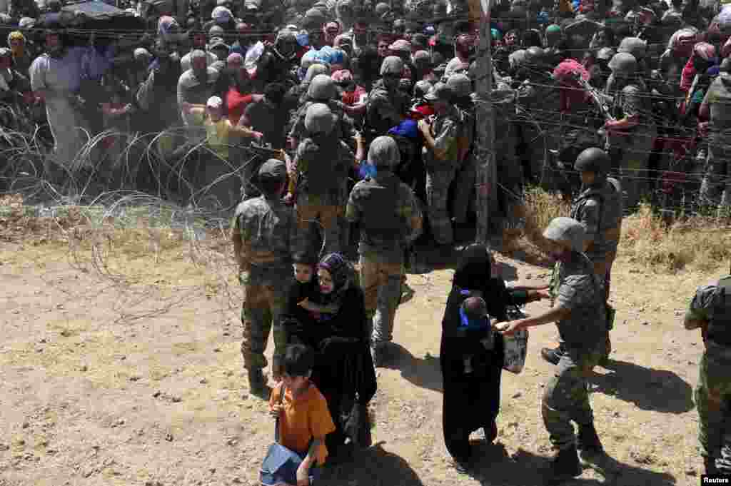 Tentara Turki membantu pengungsi Suriah ketika mereka menyeberangi perbatasan ke Turki, dekat sebelah tenggara kota Akcakale di provinsi Sanliurfa, Turki. Lebih dari 3.000 warga Suriah yang melarikan diri dari bentrokan antara tentara ISIS dan Kurdi, telah menyebrang ke Turki, menurut pejabat pemerintah Turki.