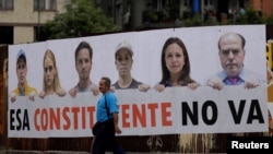 A man walks past a banner which reads "The Constituent Assembly will not happen," in Caracas, Venezuela, July 24, 2017. Pictured on the banner are opposition leaders.