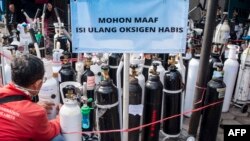 Seorang pria menunggu di depan tanda 'pasokan oksigen habis' di sebuah lokasi isi ulang oksigen di Yogyakarta, 14 Juli 2021. (Foto: Agung Supriyanto/AFP)
