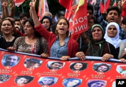 FILE - Mourners chant slogans as they carry a banner with pictures of victims of an explosion in Suruc, southeastern Turkey, during a protest in Istanbul, July 22, 2015. The suicide bombing, which killed 32 people and wounded scores, is part of a retaliation campaign by the Islamic State group for the government's crackdown on its operations in Turkey, say Turkish officials.