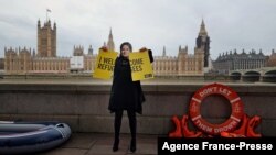 An activist from Amnesty International wearing a mask depicting Britain's Home Secretary Priti Patel, demonstrates ahead of the Government's Nationality and Borders Bill, opposite the Houses of Parliament, on the banks of the River Thames in London on Dec. 7, 2021.