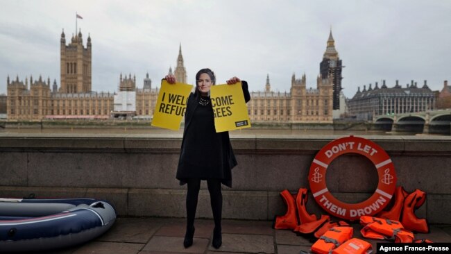 An activist from Amnesty International wearing a mask depicting Britain's Home Secretary Priti Patel, demonstrates ahead of the Government's Nationality and Borders Bill, opposite the Houses of Parliament, on the banks of the River Thames in London on Dec. 7, 2021.