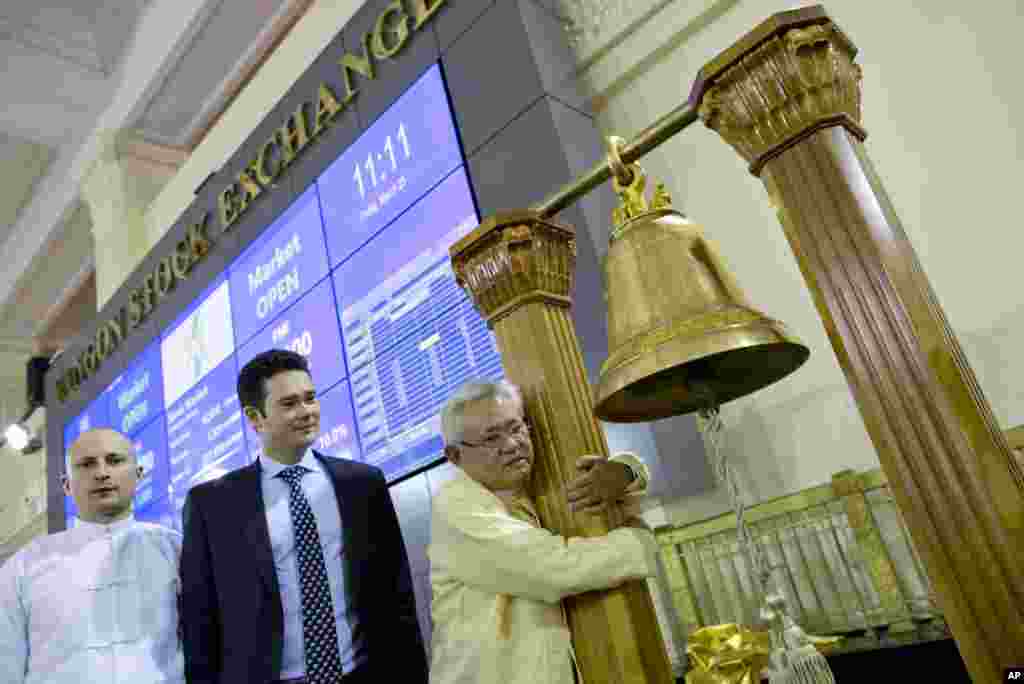 Serge Pun, right, executive chairman of First Myanmar Investment, joyfully hugs a bell pillar as electronic trading commences listing his company during the opening day of trading at Yangon Stock Exchange in Yangon, Myanmar.