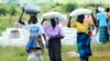 Des femmes transportent des sacs de maïs lors d'une distribution d'aide alimentaire à Mudzi, à environ 230 kilomètres au nord-est de la capitale Harare, Zimbabwe, le 20 février 2020.