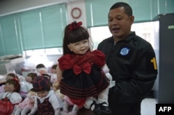 A Thai policeman shows a "luuk thep" (child angel) doll after more than a hundred of them were seized in separate raids, at the Economic Crime Suppression Division in Bangkok, Jan. 26, 2016.