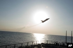 In this photo provided by the U.S. Navy, a Russian Sukhoi Su-24 attack aircraft makes a low altitude pass by the USS Donald Cook in the Baltic Sea, April 12, 2016.