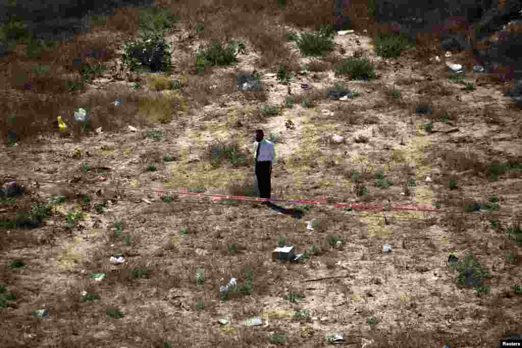 An ultra-Orthodox Jewish man stands behind a cordoned off area near a petrol station that was hit by a rocket in the southern city of Ashdod, July 11, 2014.