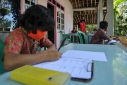 Henrikus Suroto (tengah), seorang guru SD, membuka kelas di rumah murid-muridnya di Magelang, Jawa Tengah, setelah sekolah terpaksa ditutup karena pandemi Covid-19, 20 Mei 2020. (Foto: AFP)