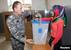 An Iraqi policeman casts his vote into a ballot box during early voting for the parliamentary election in Kirkuk, north of Baghdad, April 28, 2014.