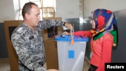 Seorang anggota pasukan keamanan Irak memberikan suara dalam sebuah TPS di Kirkuk, utara Baghdad, Senin (28/4). 