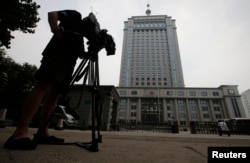 FILE - A television cameraman films the exterior of Jinan Municipality People's Intermediate Courthouse.