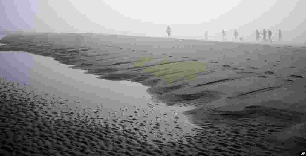 People disappear in the mist as they walk on the North Sea beach near Schoorl, northwestern Netherlands. The Netherlands enjoyed its first real spring weather with temperatures going up to 18 degrees Celsius or 65 degrees Fahrenheit.