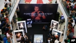 Filipino fans look at memorabilia from the "Thrilla in Manila" World Heavyweight boxing fight between Muhammad Ali and Joe Frazier at the launch of an exhibit at The Ali Mall in suburban Quezon city northeast of Manila, Philippines to pay tribute to Muhammad Ali who died exactly a week ago Friday, June 10, 2016. 