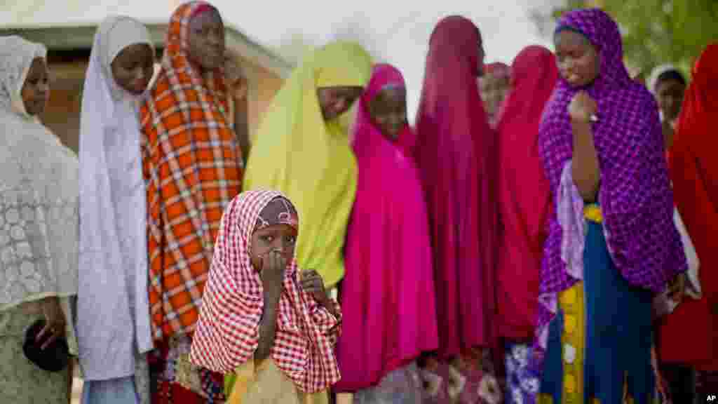 Une petite fille nigériane de la tribu Hausa se tient près de la file où sa mère est alignée avec d&rsquo;autres électeurs, attendant la validation de leur carte de vote, à un bureau de vote situé dans une école islamique de Daura, ville natale du candidat de l&#39;opposition le général Muhammadu Buhari, samedi 28 mars 2015.