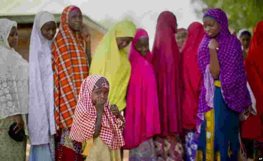 Seorang gadis kecil Nigeria dari suku Hausa menemani ibunya mengantre untuk melakukan validasi kartu pemilih, di sebuah TPS di sekolah Islam di Daura, tempat asal calon presiden Jenderal Muhammadu Buhari (28/3). (AP/Ben Curtis)