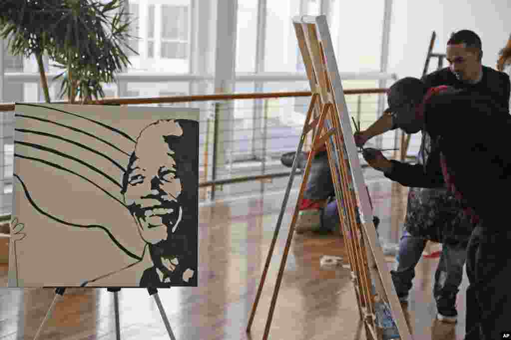 The face of former South African President Nelson Mandela is displayed as people paint during his birthday celebrations in Cape Town, South Africa.