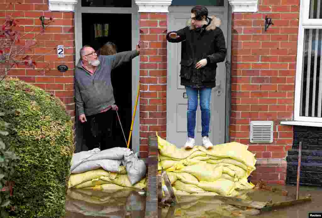 Residents chat by the sandbags at their front doors in a flooded area of Bentley, north of Doncaster, Britain.