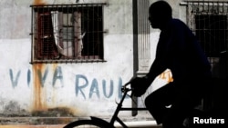 A man rides his bicycle near a graffiti that reads, "Long live Raul," in Havana, Cuba, Dec. 19, 2014. 