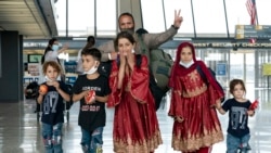 Families evacuated from Kabul, Afghanistan, walk through the terminal before boarding a bus after they arrived at Washington Dulles International Airport, in Chantilly, Va., on Friday, Aug. 27, 2021. (AP Photo/Jose Luis Magana)