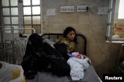 FILE - Neelum, 19, lies with her newborn at a maternity ward in Karachi, Oct. 25, 2011.