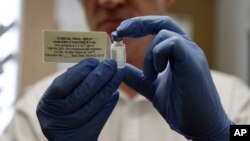 FILE - A researcher holds a vial of an experimental Ebola vaccine in Oxford, England, Sept. 17, 2014.