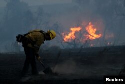 A firefighter works to put out hot spots on a fast-moving wind-driven wildfire in Orange, Calif., Oct. 9, 2017.