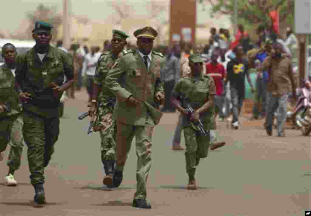 Supporters of the recent military coup look as soldiers run toward the international airport, where coup leader Capt. Amadou Haya Sanogo had been due to meet a delegation of West African presidents, in Bamako, Mali Thursday, March 29, 2012.