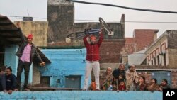FILE - A supporter lifts a bicycle, the party symbol of the Samajwadi Party (SP), during a joint election campaign rally by Uttar Pradesh state.