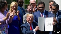 El presidente Donald Trump holds up an executive order that he signed during a National Day of Prayer event in the Rose Garden of the White House in Washington, May 3, 2018.