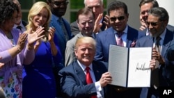 President Donald Trump holds up an executive order that he signed during a National Day of Prayer event in the Rose Garden of the White House in Washington, May 3, 2018.