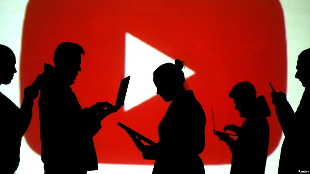 In this file photo, silhouettes of laptop and mobile device users are seen next to a screen projection of the YouTube logo in this picture illustration taken March 28, 2018. (REUTERS/Dado Ruvic/Illustration/File Photo)