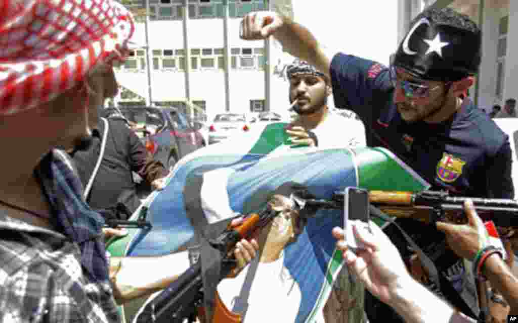 Libyan rebel fighters from Tripoli brigade deface a portrait of Libyan dictator Moammar Gadhafi in Tripoli, Libya, August 22, 201. (AP)