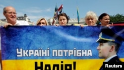 Activists hold a banner with a portrait of Ukrainian woman pilot, Nadezhna Savchenko, and the slogan, "Ukraine needs Nadia!" during a protest in Kiev July 11, 2014. Savchenko, 33, was seized by rebels in June while she was fighting with pro-government mil