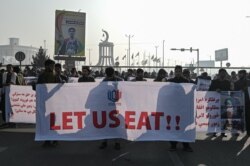 People hold a banner reading 'Let us eat' before marching down the street during a protest in Kabul, Afghanistan, Dec. 21, 2021, as the country struggles with a deep economic crisis.