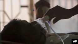 FILE -A relative adjusts the oxygen mask of a tuberculosis patient at a TB hospital on World Tuberculosis Day in Hyderabad, India, March 24, 2018. 