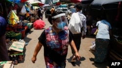 ရန်ကုန်မြို့ရှိ ဈေးတခုတွင် တွေ့ရတဲ့ နှာခေါင်းစည်းရော၊ Face Shield ရော တပ်ထားတဲ့ အမျိုးသမီးတဦး။ (ဧပြီ ၂၁၊ ၂၀၂၀)