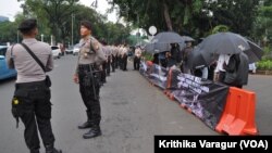 Indonesian police guard the Kamisan protesters, about 100 meters away from the Presidential Palace in Jakarta, Indonesia, July 13, 2017. 