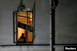 A member of French judicial police inspects the apartment raided by French police special forces earlier in Saint-Denis, near Paris, during an operation to catch fugitives from Friday night's deadly attacks in the French capital, Nov. 18, 2015.