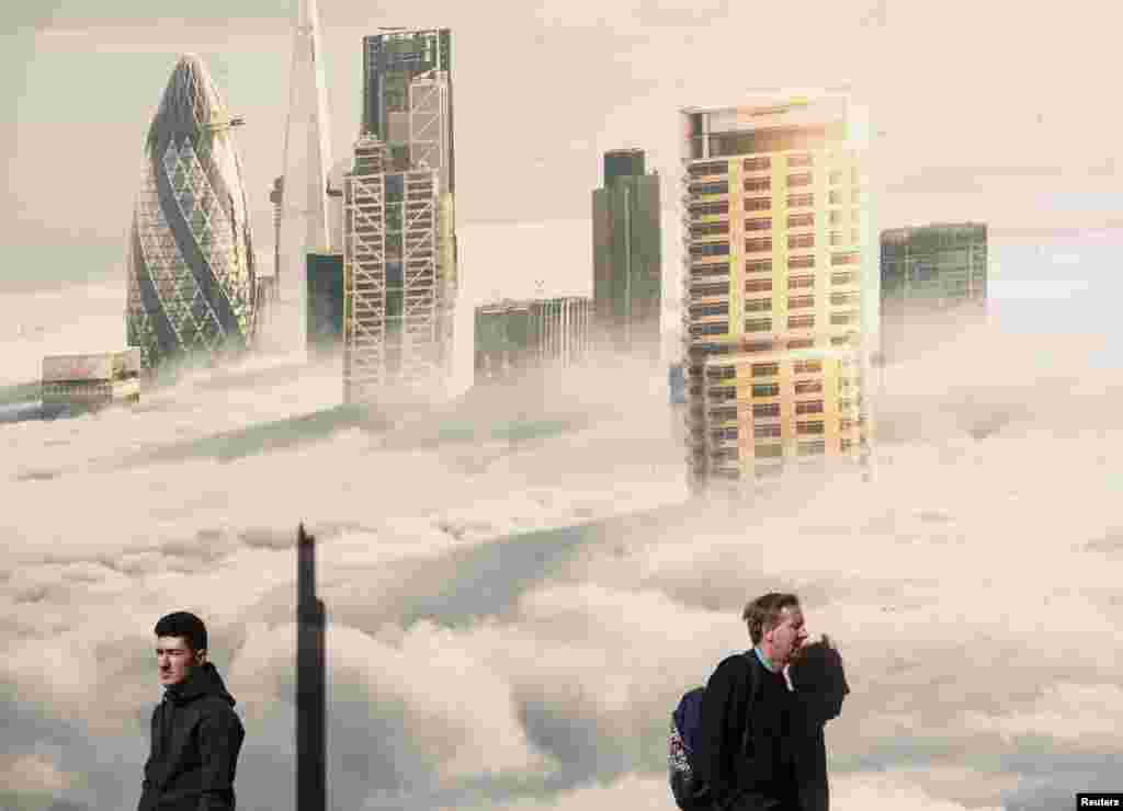 Men walk past an image of the City shrouded in fog, on a sunny spring day in London, April, 14, 2015.