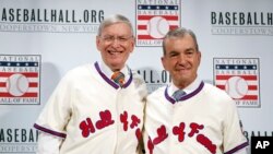 El excomisionado de Béisbol Bud Selig (izq.) y el presidente de los Bravos de Atlanta, John Schuerholz. posan con las camisetas del Salón de la Fama, tras haber sido anunciados como parte de la Clase 2017 del Salón de la Fama del Béisbol.