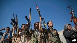 Tribesmen loyal to Houthi rebels hold up their weapons as they attend a gathering to show their support for the ongoing peace talks being held in Sweden, in Sanaa, Yemen, Dec. 13, 2018.