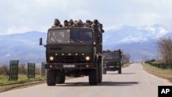 Ethnic Armenian fighters stand in backs of Kamaz military trucks on their way to a frontline at Martakert province in the separatist region of Nagorno-Karabakh, Azerbaijan, Monday, April 4, 2016.
