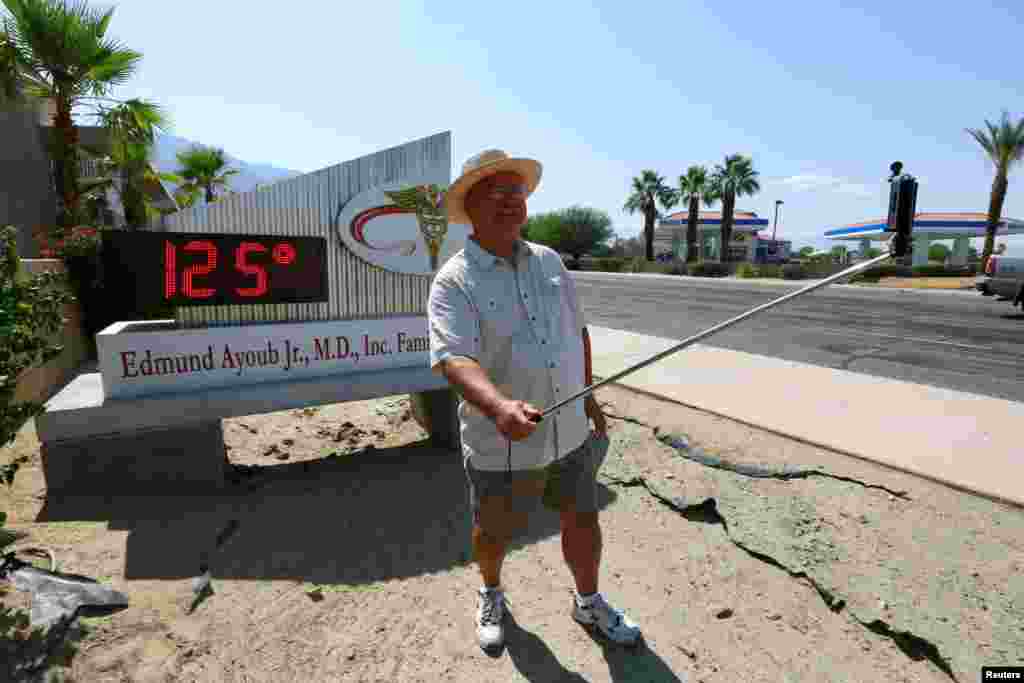 Benito Almojuela takes a selfie near a thermometer sign that reads 125 degrees, in Palm Springs, California, June 20, 2016.