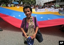 A woman holds a Virgin Mary statue during a protest march during a protest march against Venezuela's President Nicolas Maduro's government and also to commemorate the country's Day of the Journalist, in Caracas, Venezuela, June 27, 2017.